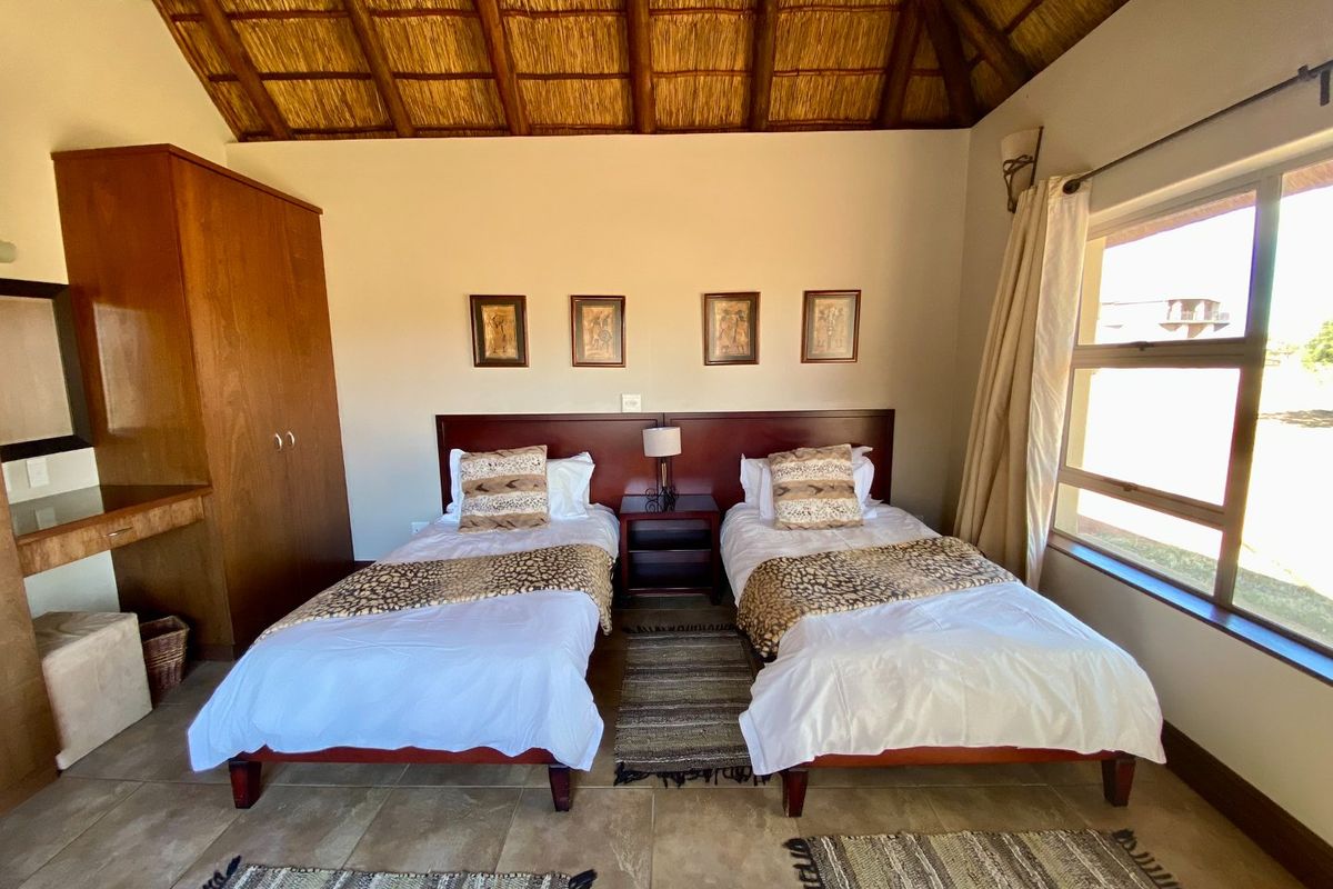 A bedroom featuring a high thatched ceiling, tiled flooring, and a built-in wooden wardrobe.