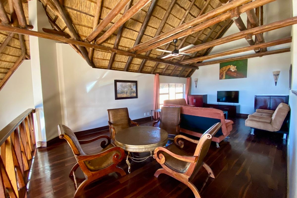 Spacious living area featuring a high vaulted thatched roof with exposed timber beams and polished dark wood flooring.