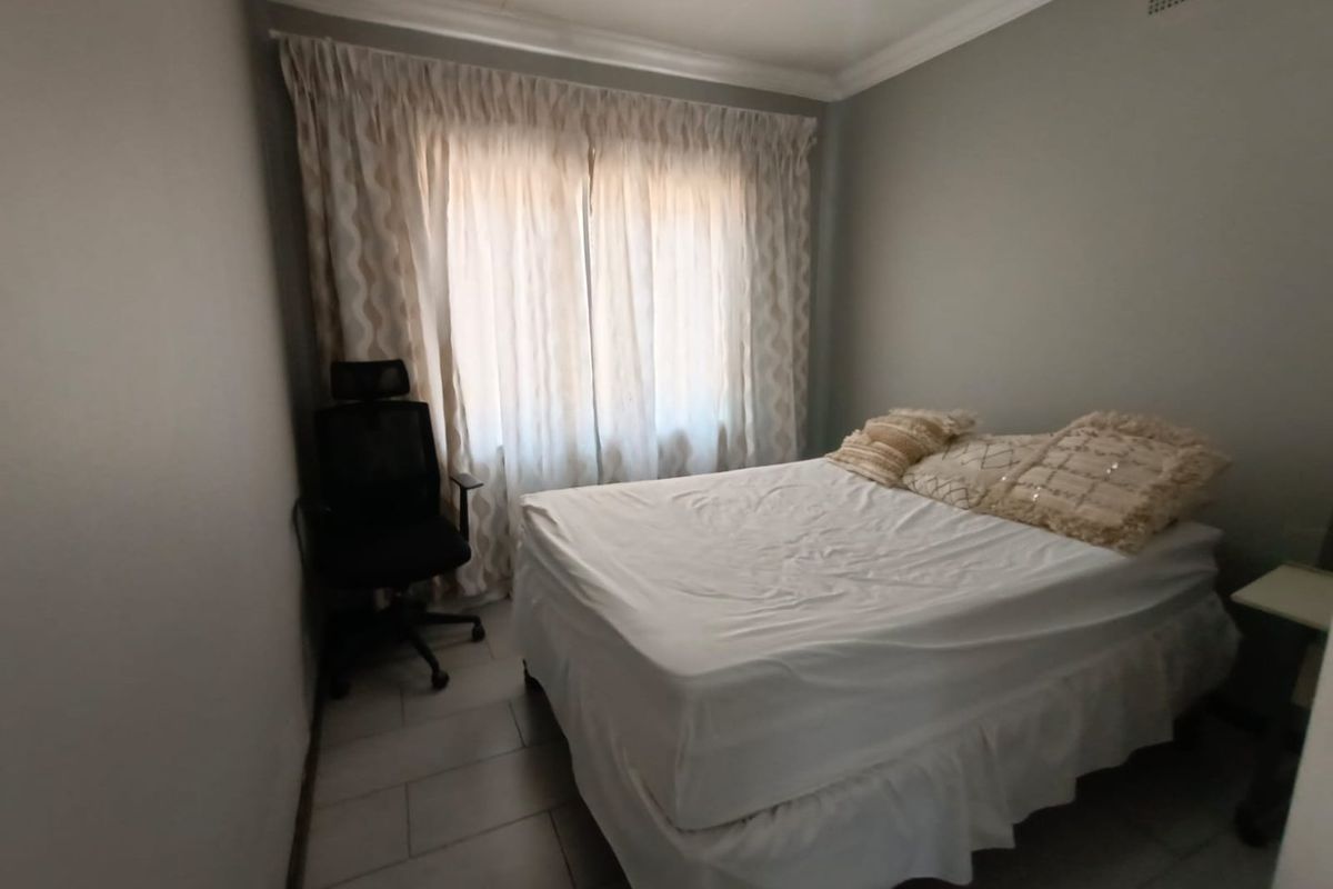 A functional bedroom featuring tiled flooring and ceiling cornice detailing, providing a neutral base for interior design updates.
