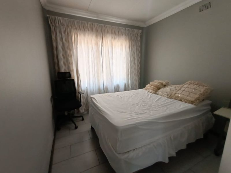 A functional bedroom featuring tiled flooring and ceiling cornice detailing, providing a neutral base for interior design updates.