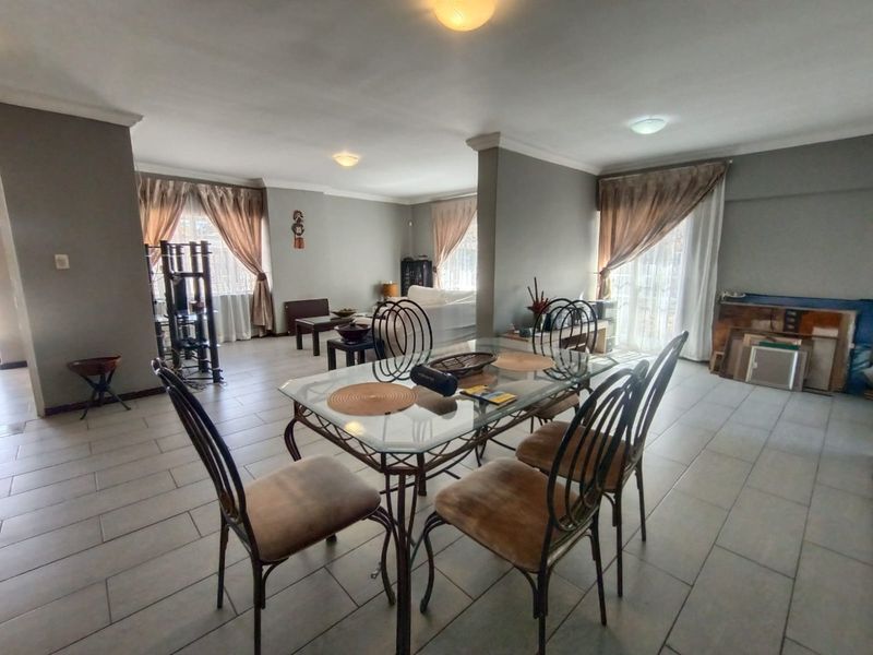 Spacious open-plan living and dining area featuring neutral tiled flooring, large sliding glass doors for natural light, and modern ceiling finishes.