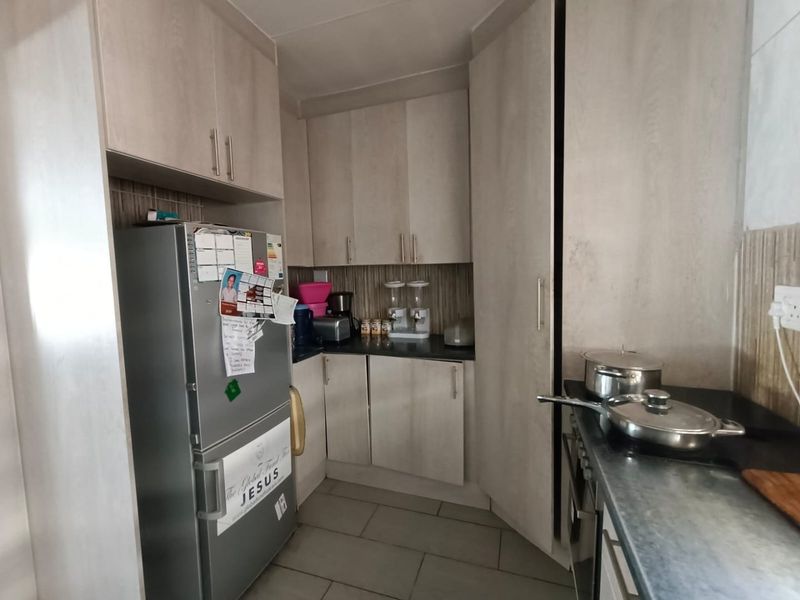 A functional kitchen featuring light-toned built-in cabinetry, dark laminate countertops, and tiled flooring, providing a practical workspace with integrated cooking appliances.
