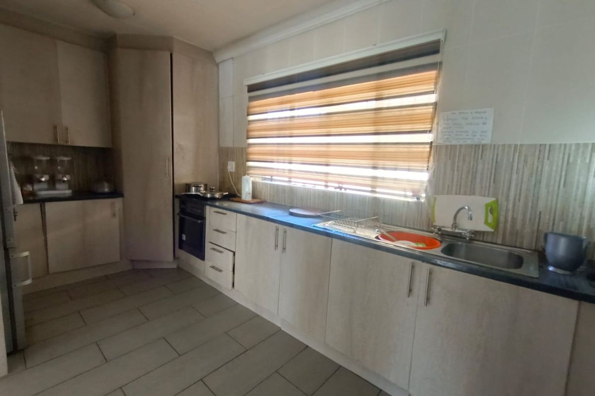 A functional kitchen featuring light-toned built-in cabinetry, laminate countertops, a stainless steel sink, and a built-in oven with tiled flooring and backsplash.