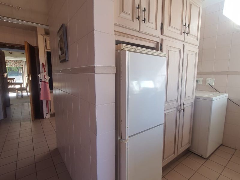 A functional laundry area featuring tiled walls and flooring with built-in cabinetry providing ample storage space.