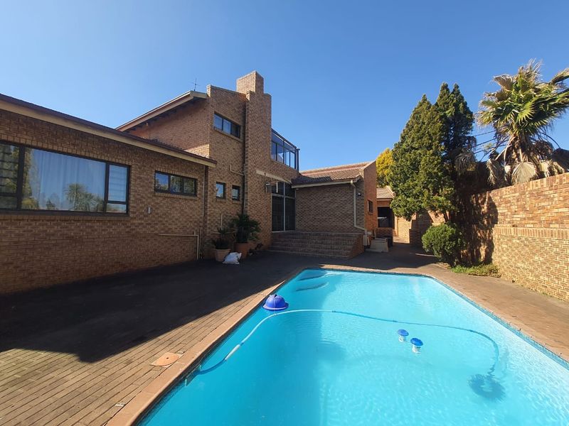 Rear exterior view featuring a swimming pool, brick facade, and paved pool deck area.