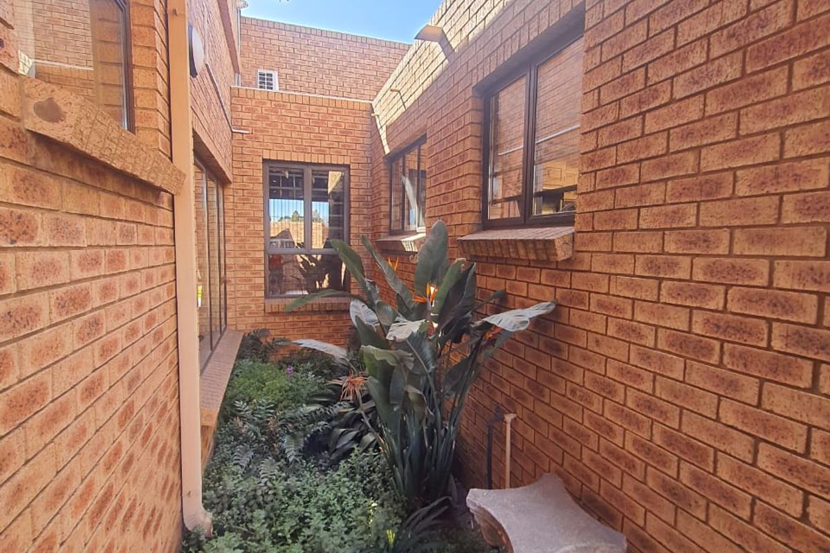 A narrow side passage or courtyard area featuring face brick walls and aluminium window frames, providing access between sections of the property.