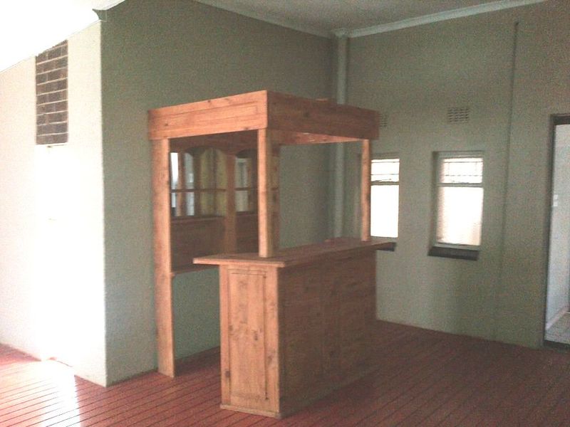 An indoor entertainment area featuring a built-in wooden bar counter and timber flooring, offering a dedicated space for hosting and social gatherings.