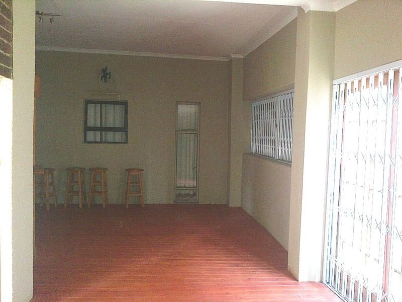 A covered outdoor patio area featuring tiled flooring, security gates, and window bars, offering a blank canvas for outdoor living space development.