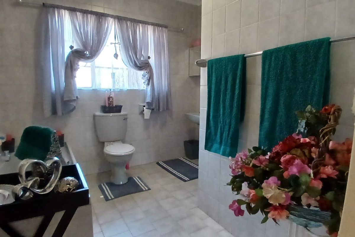 A functional bathroom featuring a standard toilet, wall-mounted basin, and tiled finishes throughout.