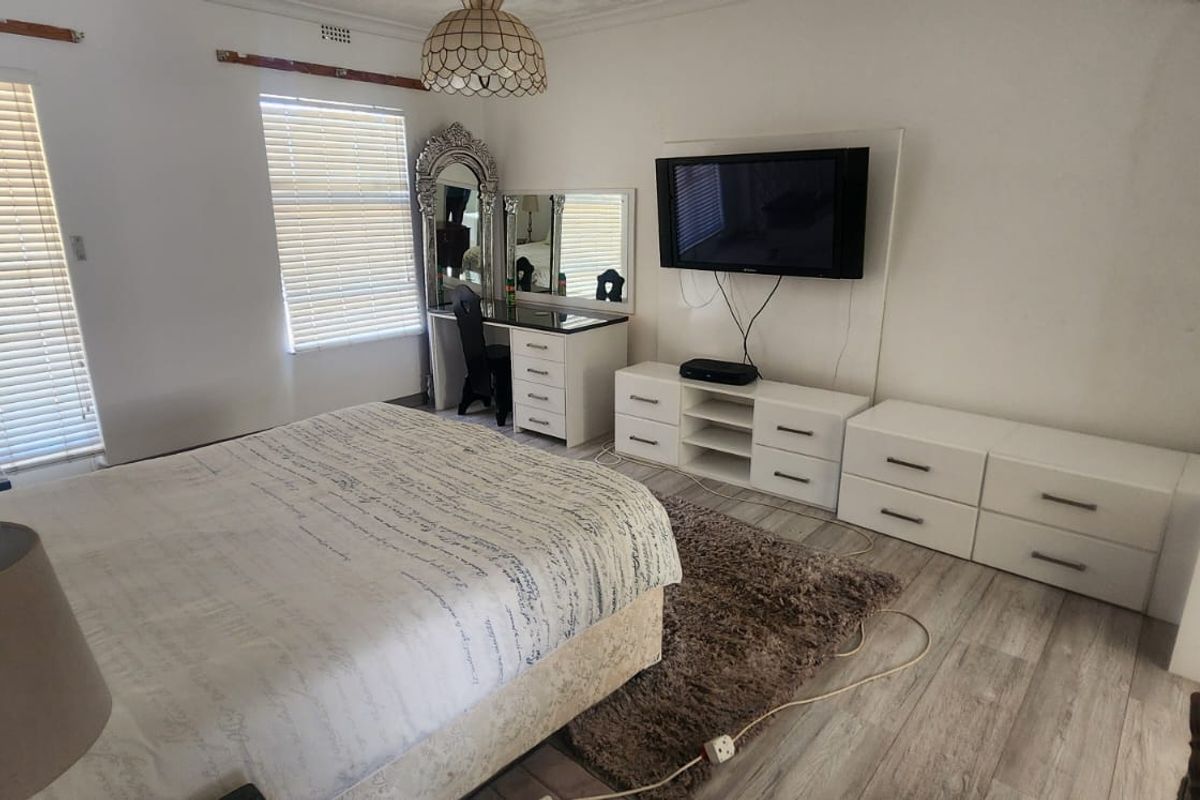 Spacious bedroom featuring light-toned wood-look flooring, dual windows with fitted blinds, and a neutral interior finish.