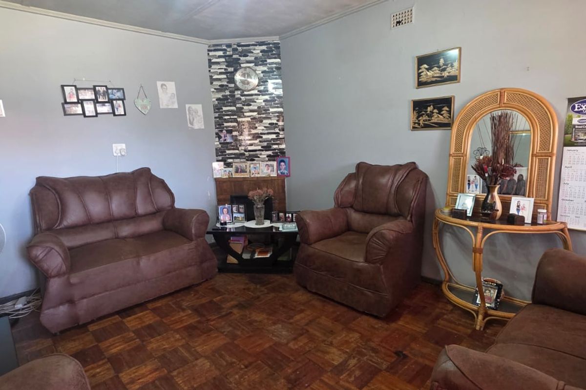 A living room featuring parquet flooring and a corner fireplace with decorative stone cladding.