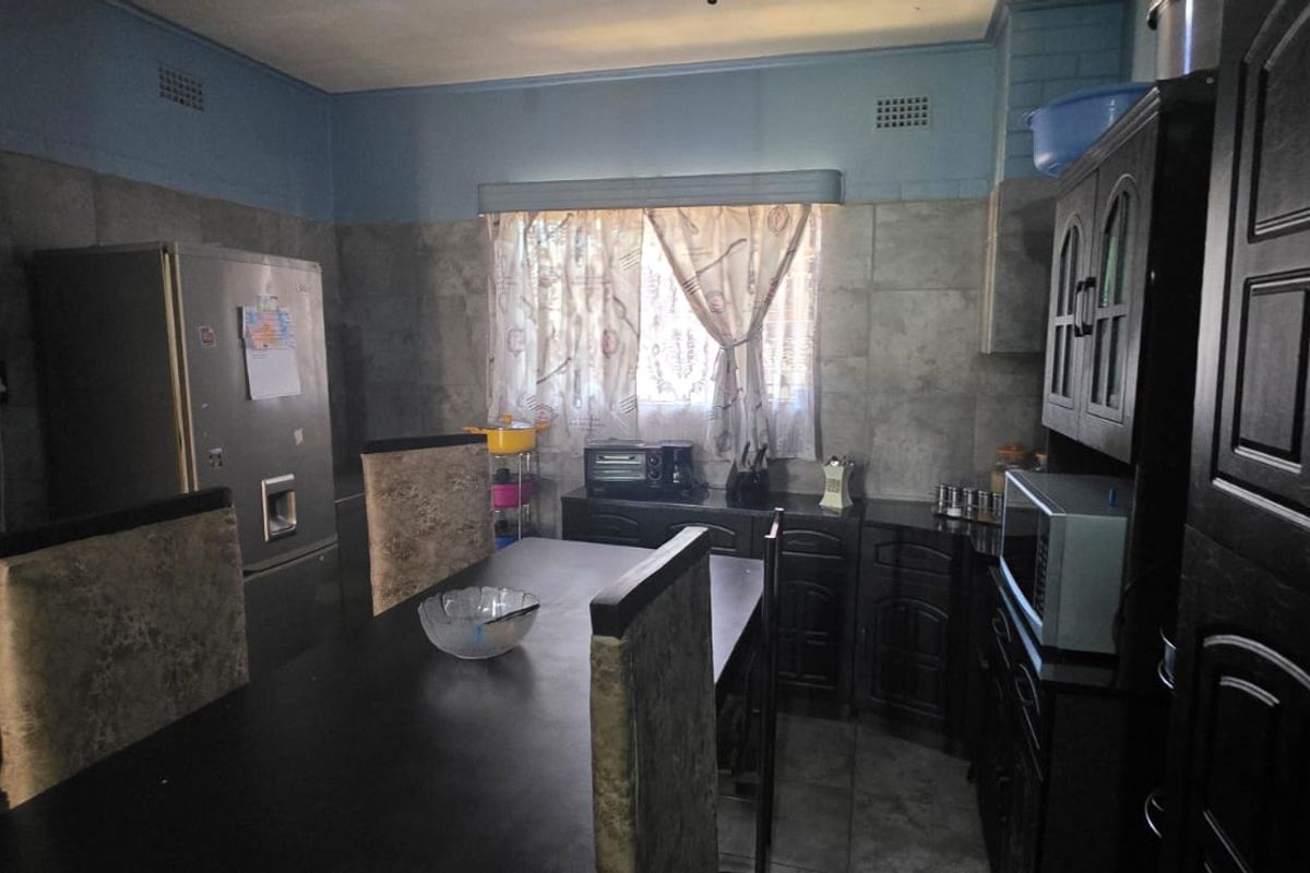 A functional kitchen featuring dark cabinetry, tiled walls, and a dedicated dining area, providing a practical space for meal preparation and family dining.