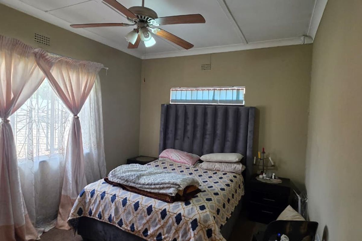 A bedroom featuring a ceiling fan, security bars on the windows, and neutral wall finishes.