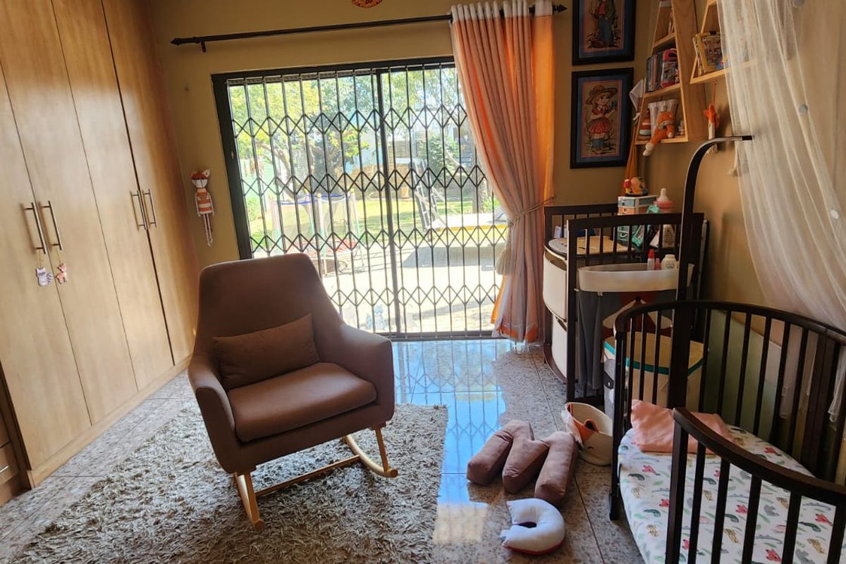 A bedroom featuring built-in wooden cabinetry, tiled flooring, and a sliding glass door with security gate providing access to the garden.