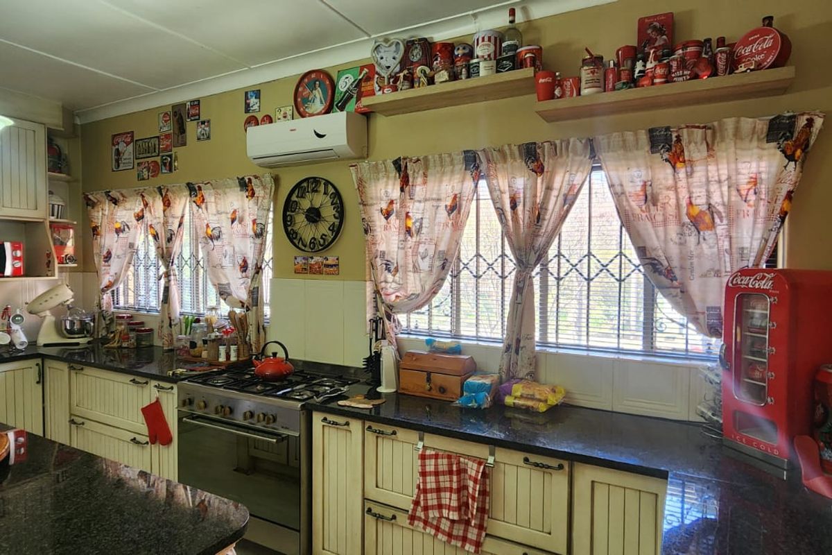 A functional kitchen featuring granite countertops, built-in cabinetry, a gas stove with extractor fan, and a wall-mounted air conditioning unit.