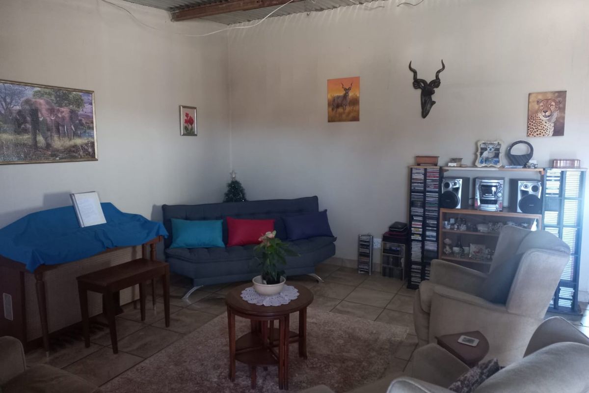 A living room featuring tiled flooring and an exposed corrugated metal ceiling, providing a rustic aesthetic within the farm property.