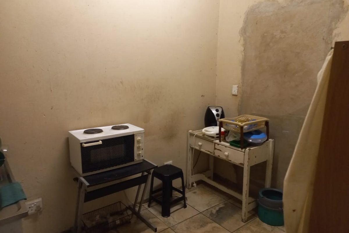 A basic utility or kitchen prep area featuring tiled flooring and exposed wall sections, requiring cosmetic updates and maintenance.