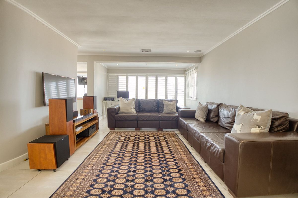 A well-lit living room featuring neutral walls, tiled flooring, and plantation shutters, providing a comfortable and functional space.