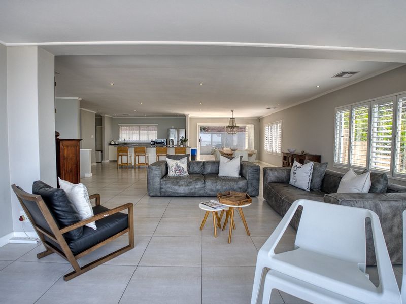 Spacious open-plan living area featuring large format floor tiles, recessed lighting, and plantation shutters, seamlessly connecting the lounge to the kitchen and dining space.
