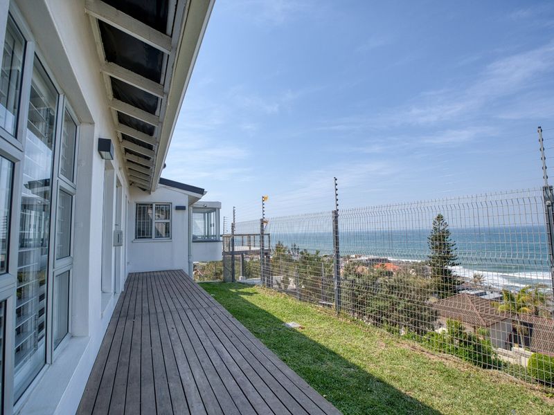 A spacious outdoor timber deck featuring secure mesh and electric fencing, offering elevated coastal views and direct access to the home's interior.