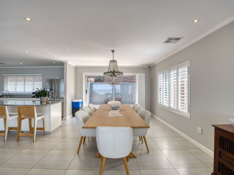 Spacious open-plan dining and kitchen area featuring tiled floors, recessed lighting, plantation shutters, and a large kitchen island with granite countertops.