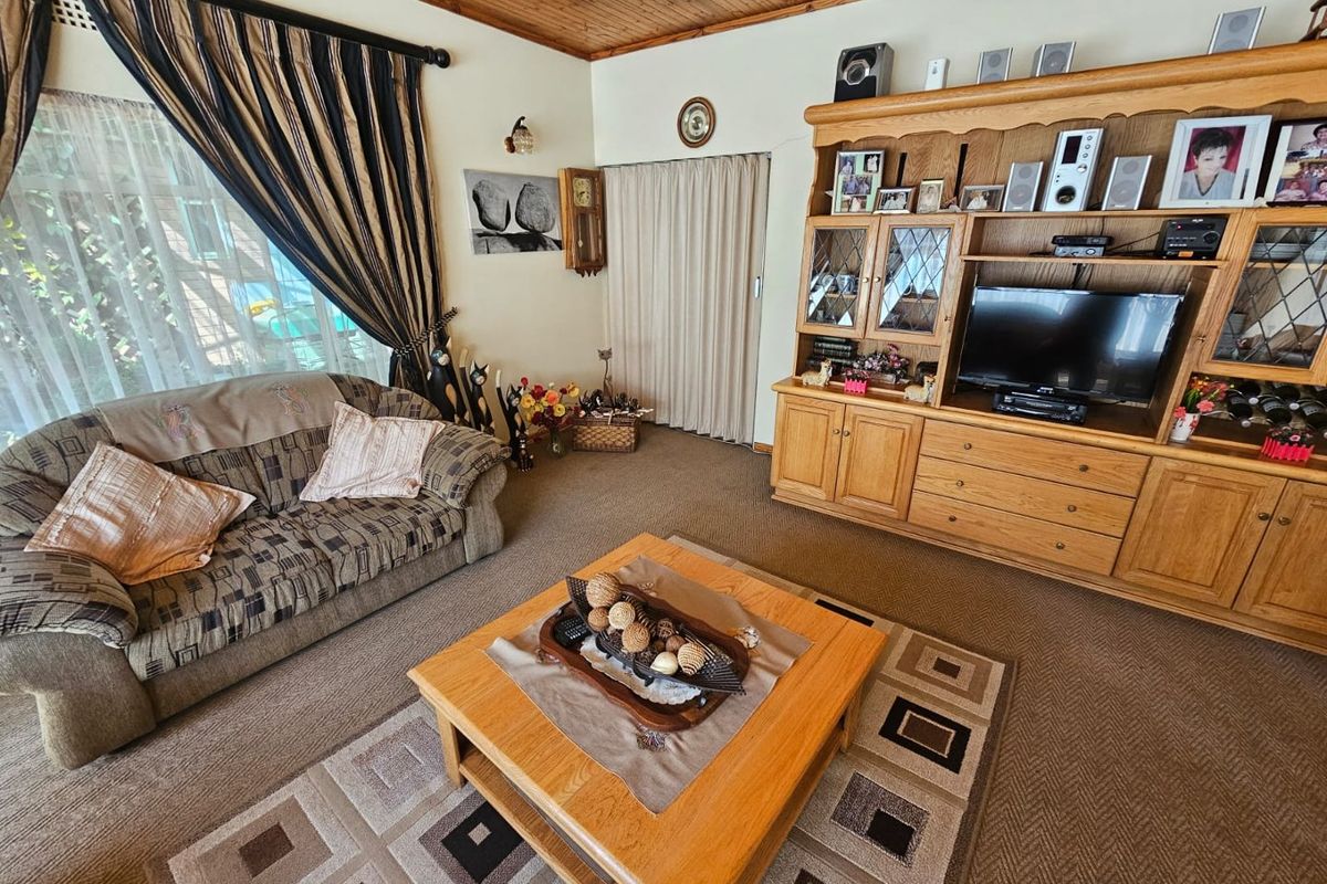 A cozy living room featuring a timber-clad ceiling, carpeted flooring, and a large built-in wooden wall unit.
