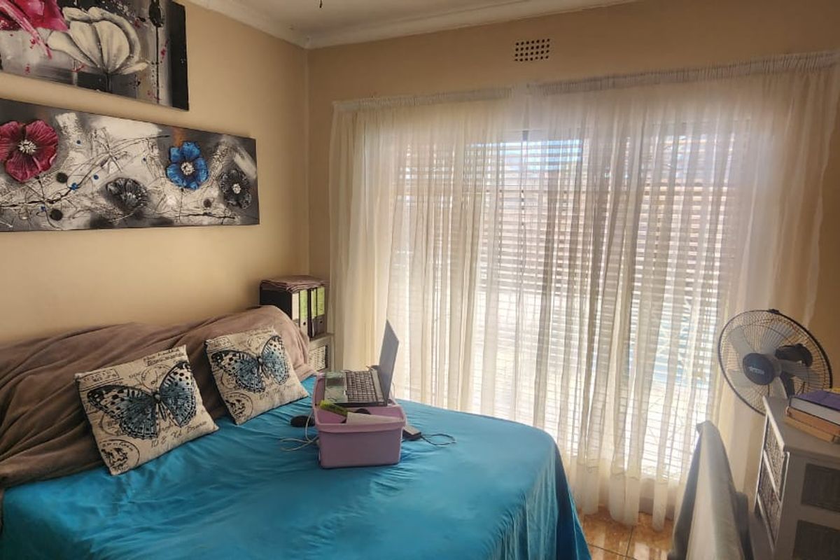 A bedroom featuring tiled flooring and a large sliding glass door with sheer curtains, providing natural light and access to the exterior.