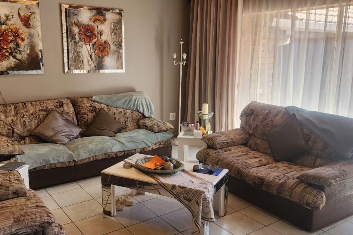 A comfortable living room featuring tiled flooring and large sliding glass doors that provide ample natural light and access to the outdoor area.