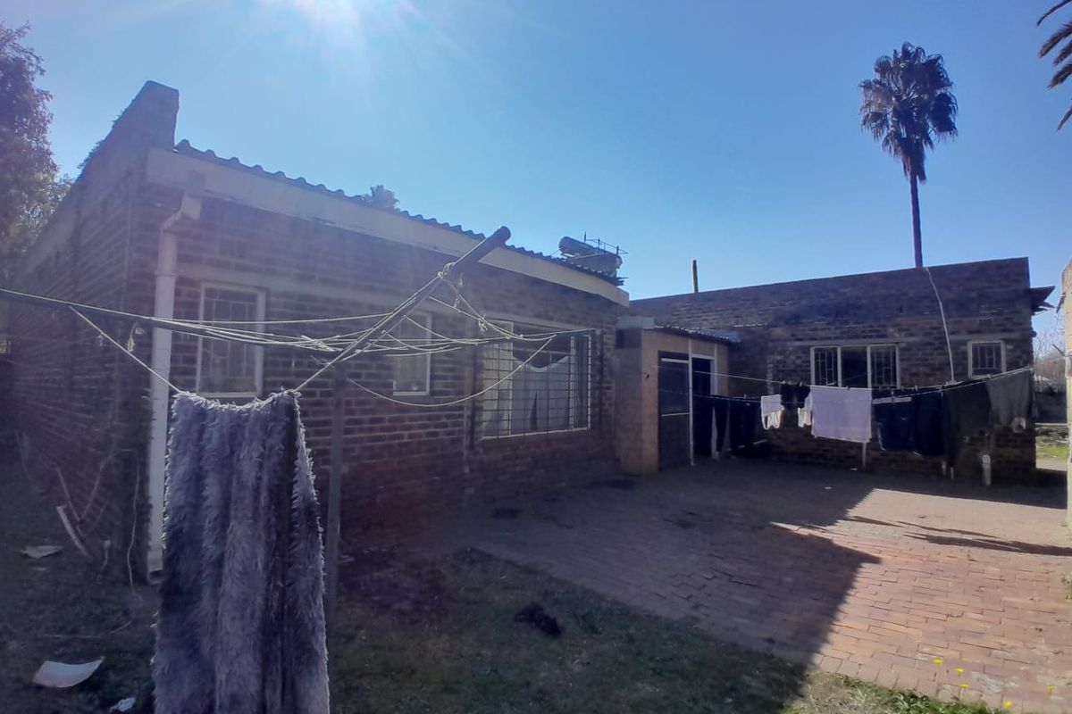 Rear view of the property featuring a brick facade, paved patio area, and installed solar water heating system.