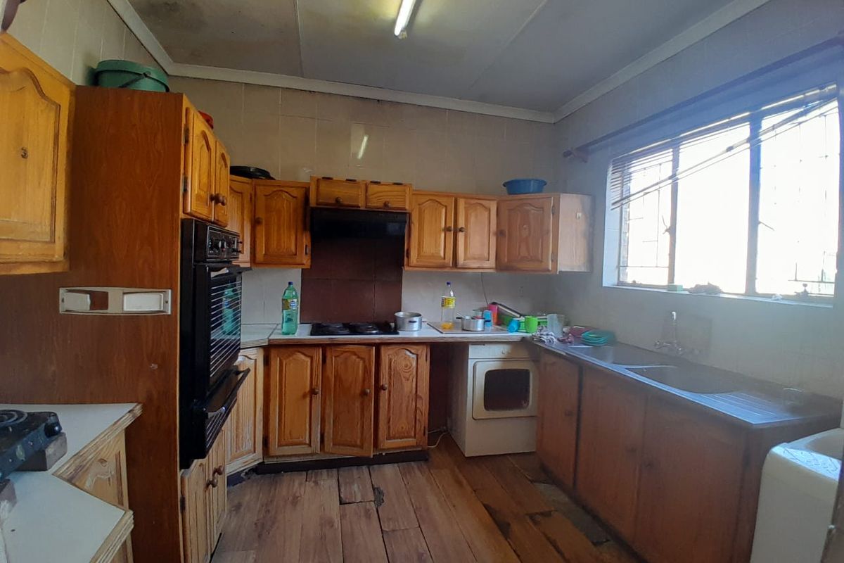A dated kitchen featuring wooden cabinetry, built-in oven, hob, and double sink, requiring renovation to modernize the space.