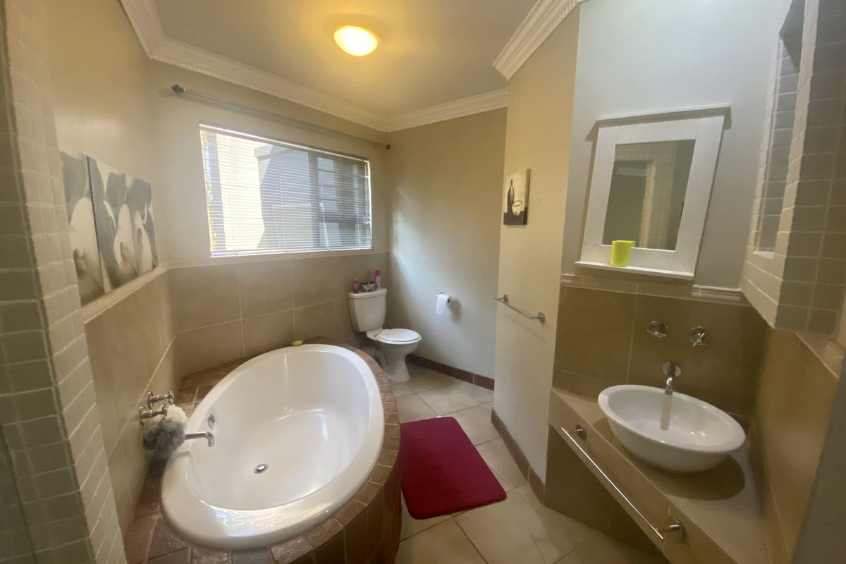 A functional bathroom featuring a built-in oval bathtub, a vessel sink vanity, and neutral wall tiling.