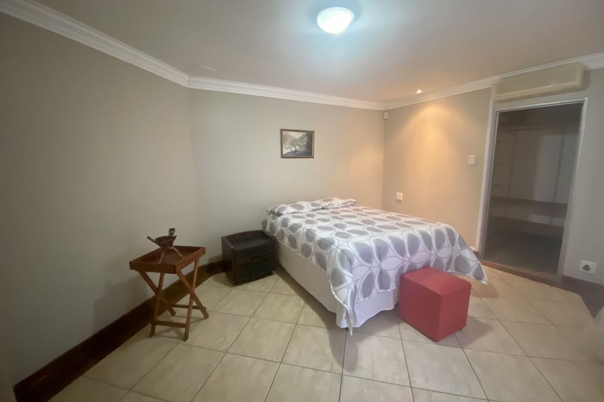 A bedroom featuring tiled flooring, crown molding, and an integrated walk-in closet area with an overhead air conditioning unit.