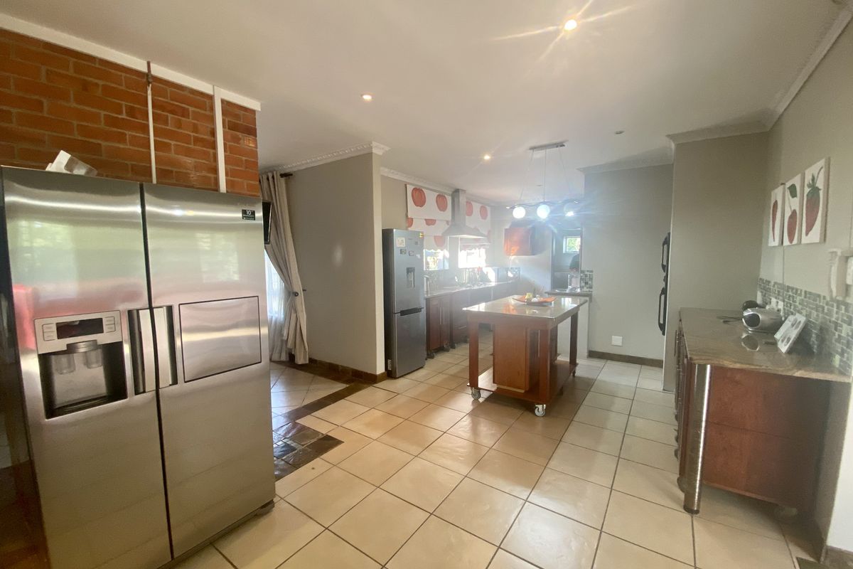 Spacious kitchen featuring a central island, tiled flooring, and built-in cabinetry, offering a functional layout with integrated appliance space.