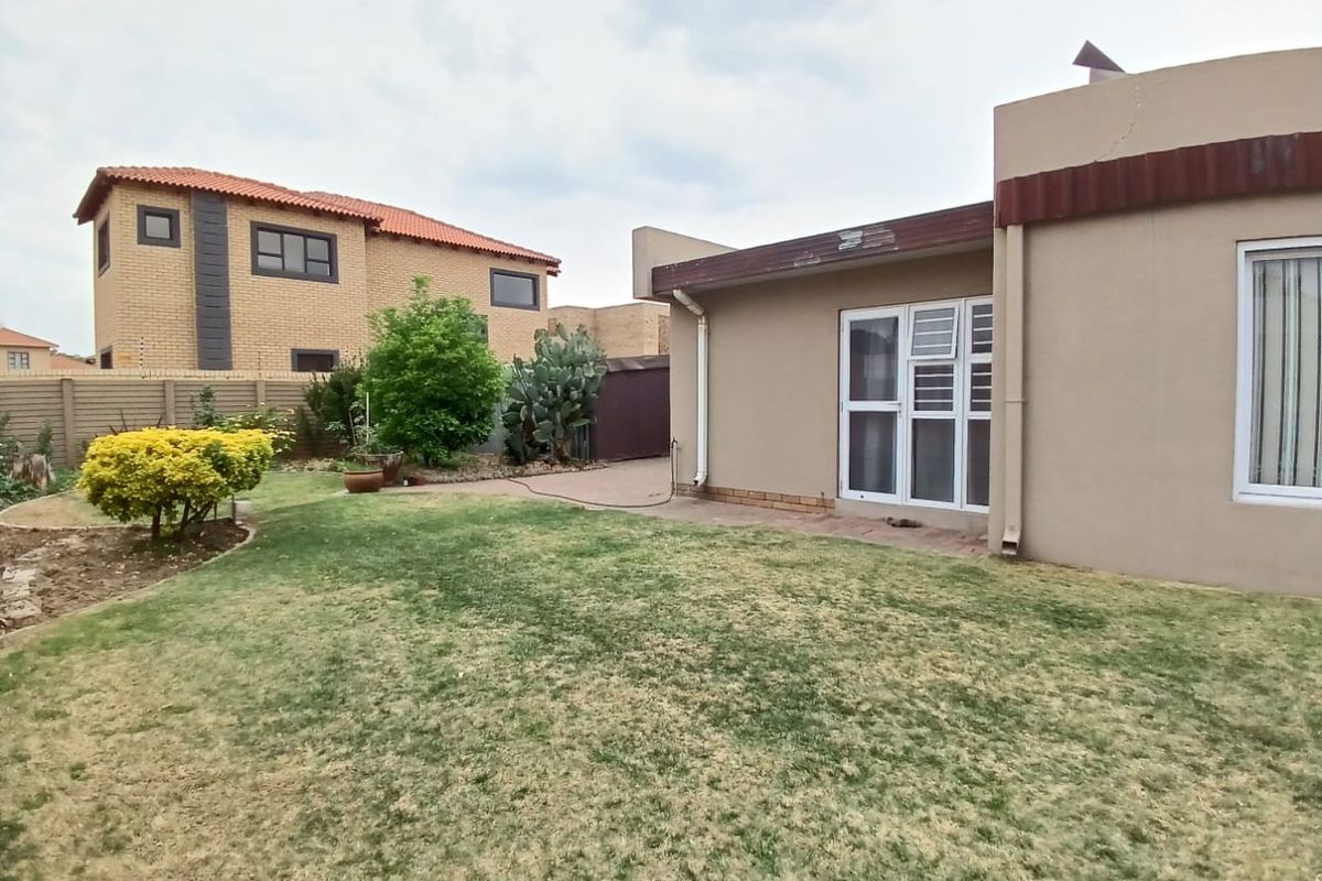 A view of the rear garden featuring a lawn area, paved patio section, and exterior wall access to the home.