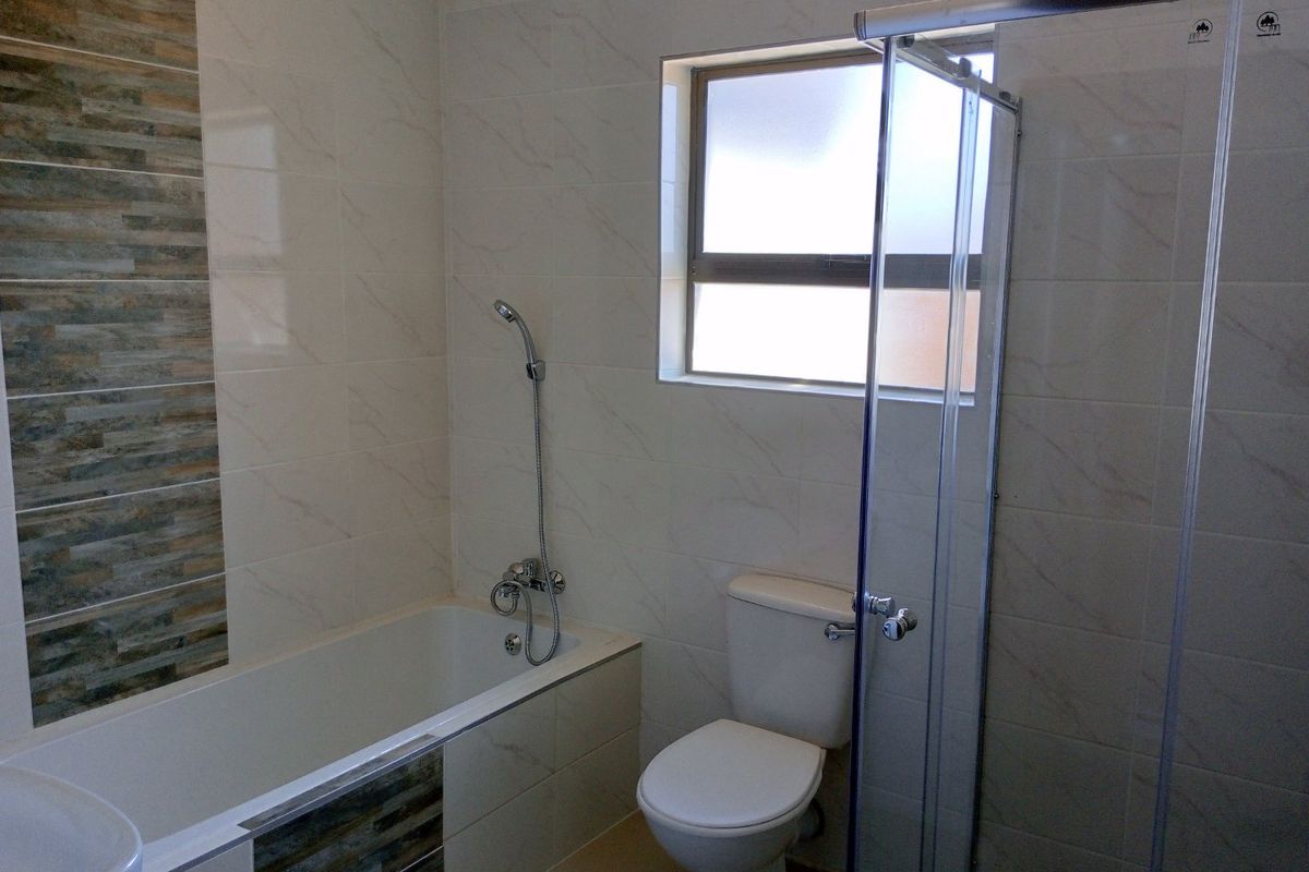 Modern bathroom featuring a built-in bathtub, separate glass-enclosed shower, and tiled walls with decorative accent detailing.