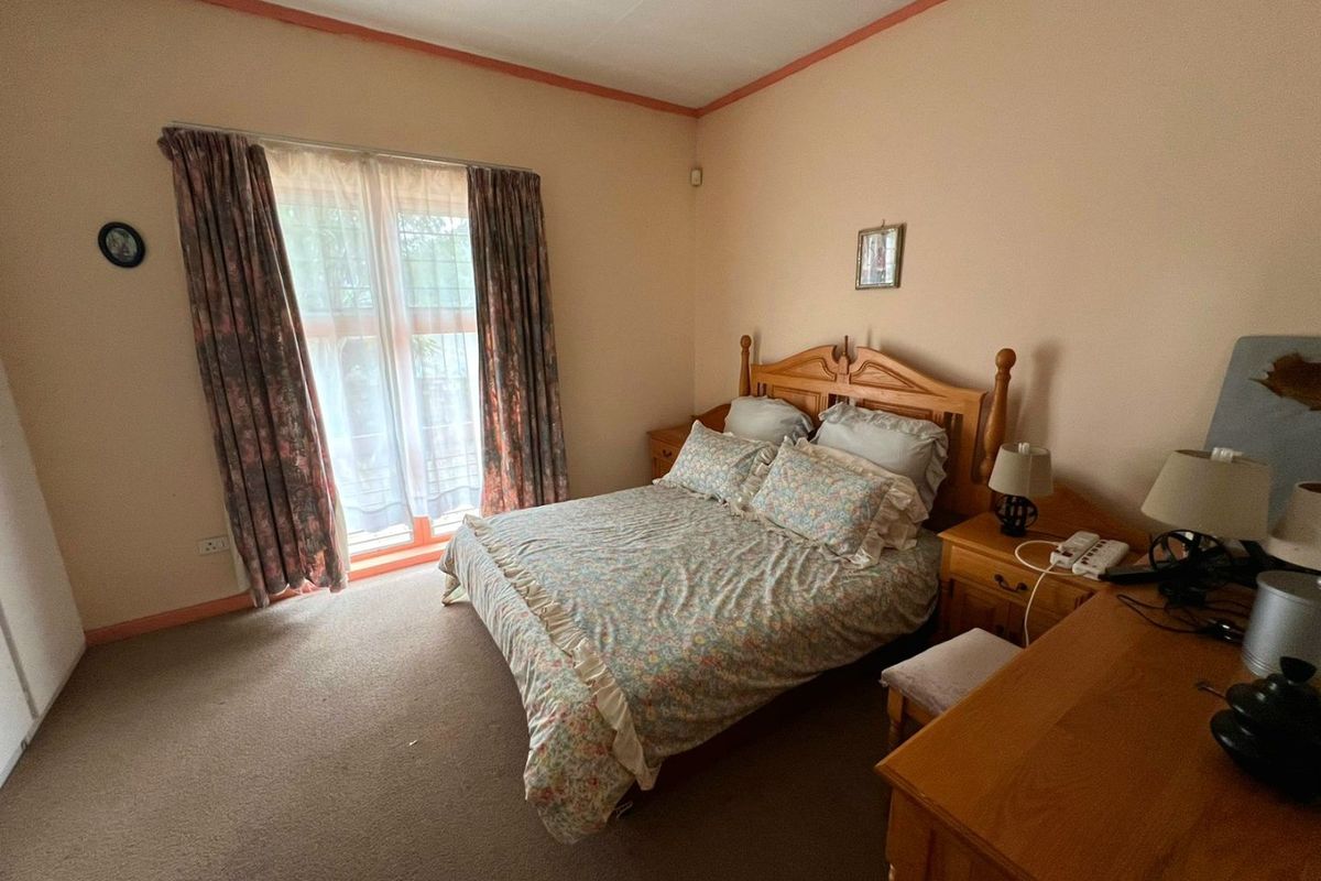 A bedroom featuring carpeted flooring, a large window with curtains, and neutral wall finishes, providing a functional and comfortable sleeping space.