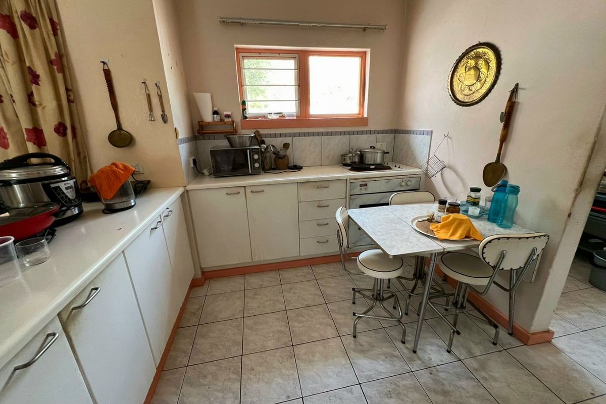 A compact kitchen featuring white cabinetry, tiled flooring, and a built-in oven with hob, offering a functional layout for meal preparation.