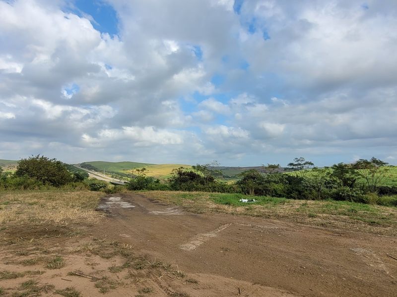 Expansive view of the surrounding rural landscape and rolling hills, featuring a dirt access track leading through the open farm property.