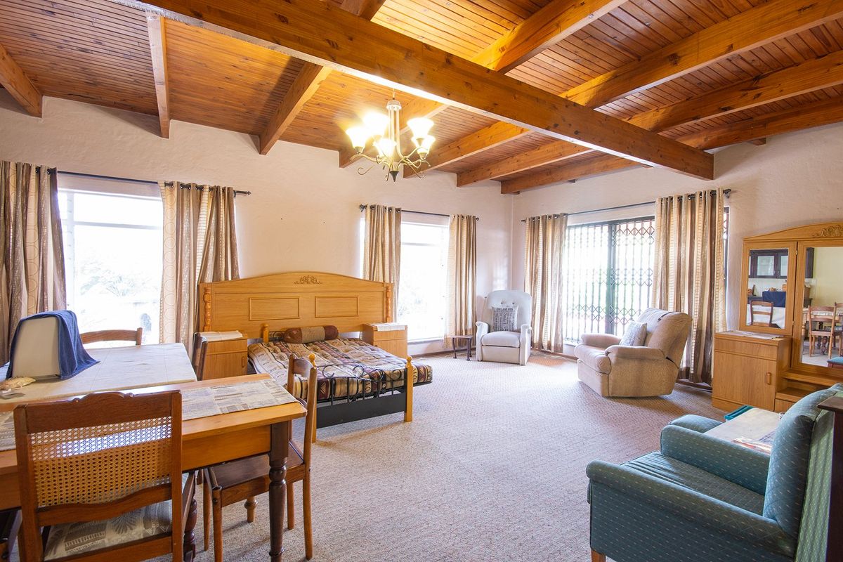 Spacious bedroom featuring exposed timber ceiling beams, a warm timber ceiling, and large windows with access to an outdoor area via a sliding door.