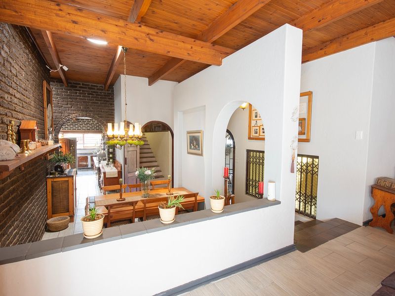 Open plan living and dining area featuring exposed timber beam ceilings, brick feature walls, and classic archway architectural details.