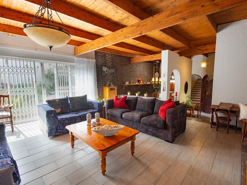 Spacious living room featuring exposed timber ceiling beams, a rustic brick feature wall, and large sliding doors leading to the outdoor area.