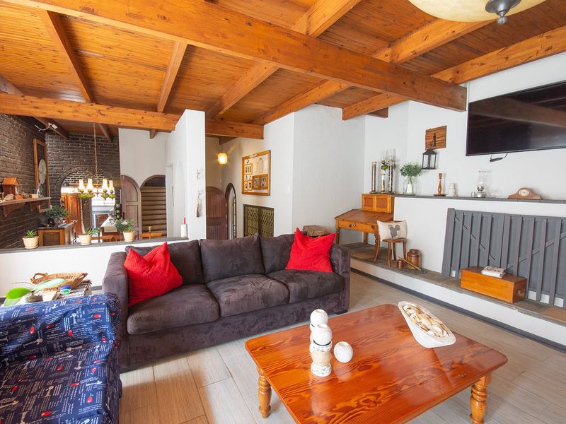 Spacious living room featuring exposed timber ceiling beams, a brick feature wall, and a built-in fireplace, creating a warm and rustic atmosphere.