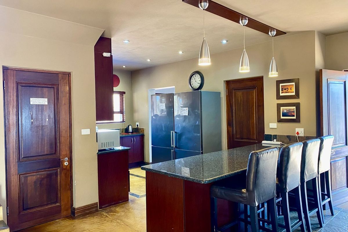 A functional kitchen featuring a dark granite breakfast bar, wooden cabinetry, recessed ceiling lighting, and pendant lights over the island.