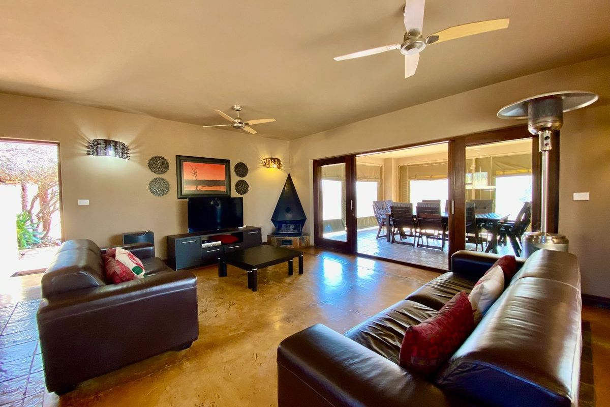 Spacious living room featuring polished concrete floors, a corner fireplace, and large sliding glass doors that open onto an outdoor patio area.