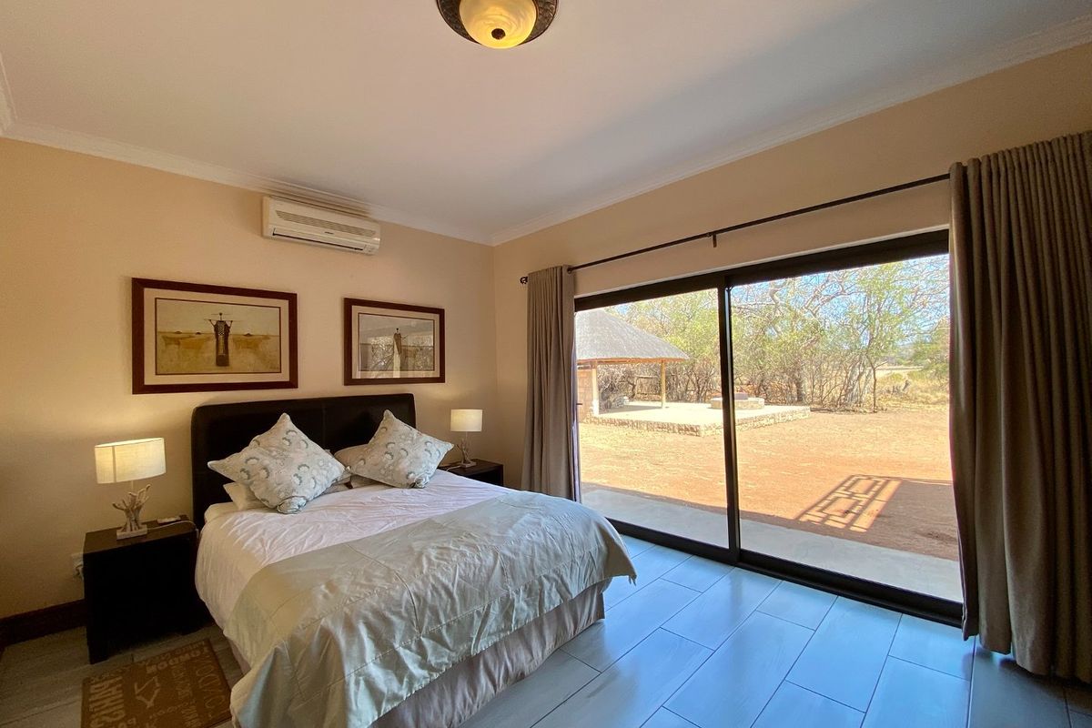 A well-maintained bedroom featuring tiled flooring, a wall-mounted air conditioning unit, and large sliding glass doors providing direct access to the outdoor area.