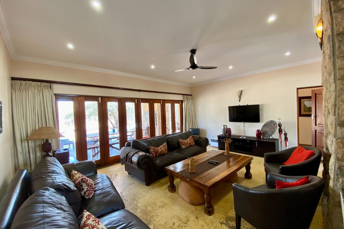 Spacious living room featuring large wooden folding doors that open to an outdoor area, recessed ceiling lighting, and a stone-accented wall.