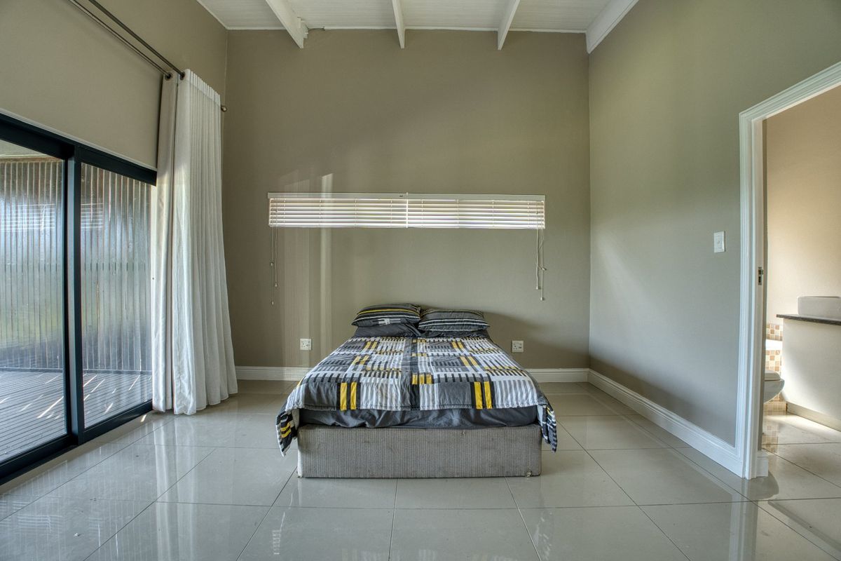 Spacious bedroom featuring high vaulted ceilings, large sliding glass doors leading to an outdoor area, and an en-suite bathroom access.