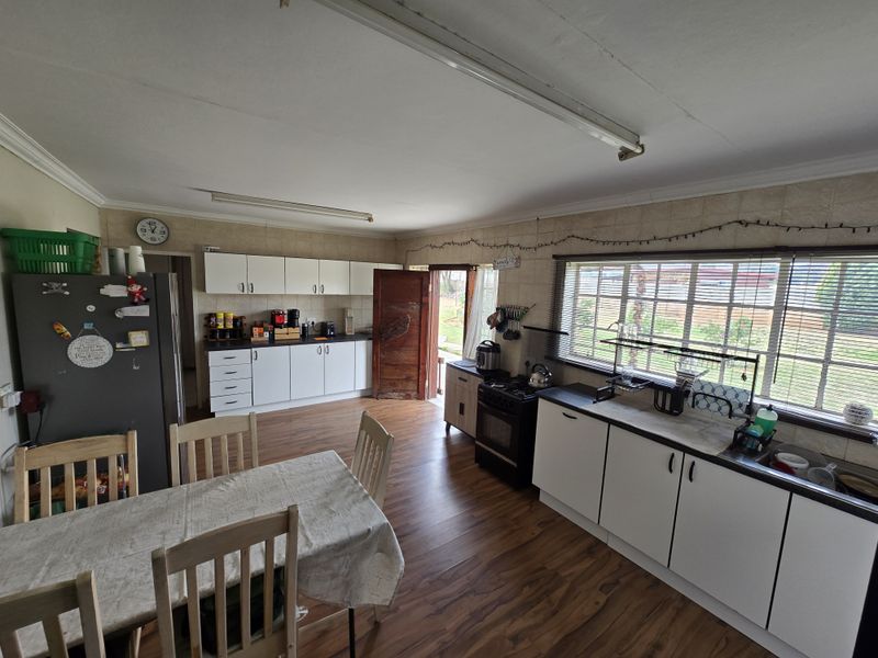 Open-plan kitchen and dining area featuring white cabinetry, laminate flooring, and a large window overlooking the farm grounds.