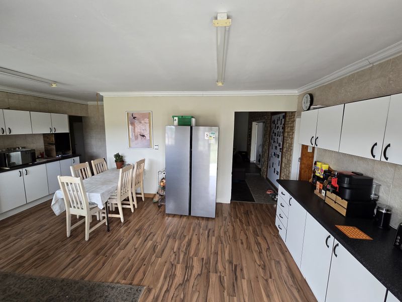 Open-plan kitchen and dining area featuring laminate flooring, white built-in cabinetry, and tiled backsplashes, offering a functional layout for family living.