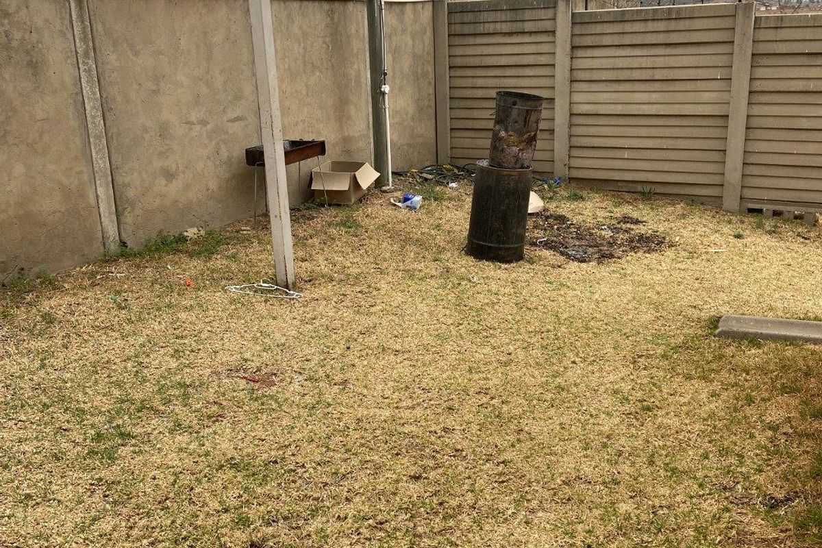 A private rear garden area featuring a precast concrete boundary wall with security electric fencing and razor wire.